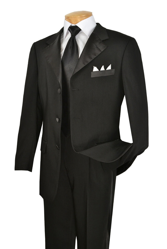 The Vinci Regular Fit 2 Piece 3 Button Tuxedo in black, from Vinci Suits, is elegantly showcased on a wooden mannequin. Accompanied by a tie and pocket square, the tuxedo's microfiber fabric ensures it remains flawless for any formal occasion.