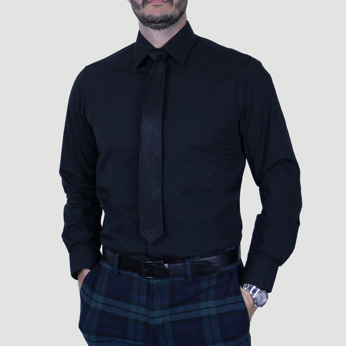 A person in an ARTURO Modern Fit Long Sleeve Black Dress Shirt, matching tie, and plaid trousers.