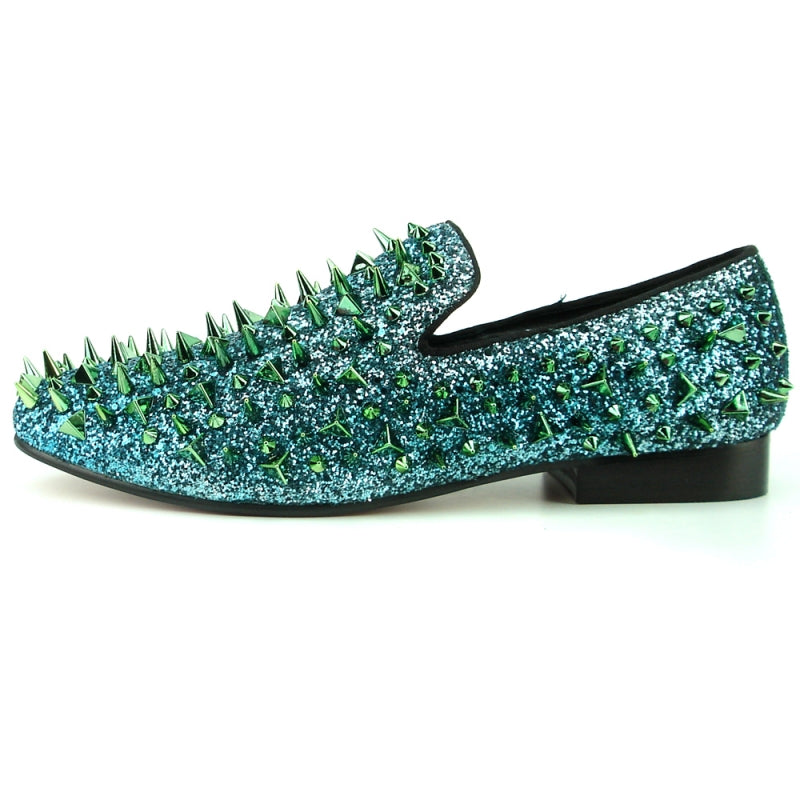 The FI-7239 from Fiesso by Aurelio Garcia showcases fashion-forward shoes featuring blue glitter loafers with a suede upper. They are adorned with striking green and gold spikes, all set on a sleek black sole.