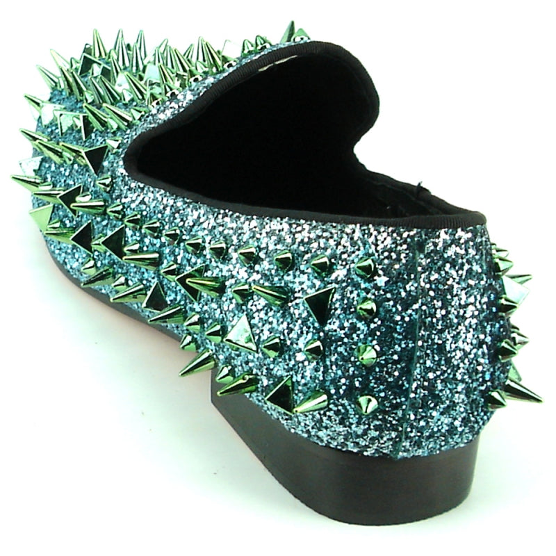 The FI-7239 from Fiesso by Aurelio Garcia showcases fashion-forward shoes featuring blue glitter loafers with a suede upper. They are adorned with striking green and gold spikes, all set on a sleek black sole.