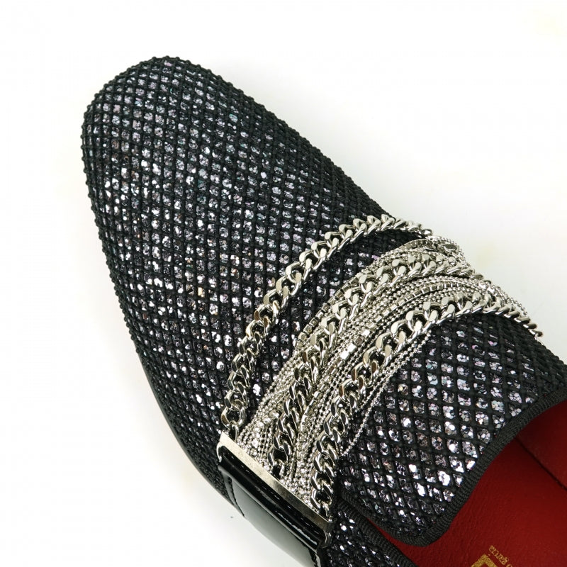 The Fiesso FI-7528 Black Silver Slip-On Loafer is a sophisticated men's dress shoe, featuring a textured leather exterior with a shiny finish. It is elegantly adorned with silver chains across the top and boasts a striking red interior lining, making it the perfect blend of modern style and elegance.