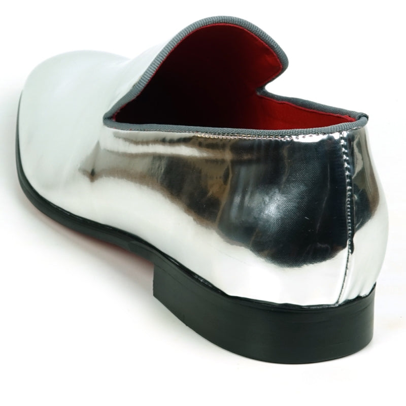 The FI-7548 Silver Patent Slip On Leafer by Fiesso embodies the sophistication of men's dress shoes with its sleek, shiny silver exterior and vibrant red interior complemented by a sturdy black sole. This elegant design seamlessly integrates the allure of vegan leather, offering both style and comfort with every step.