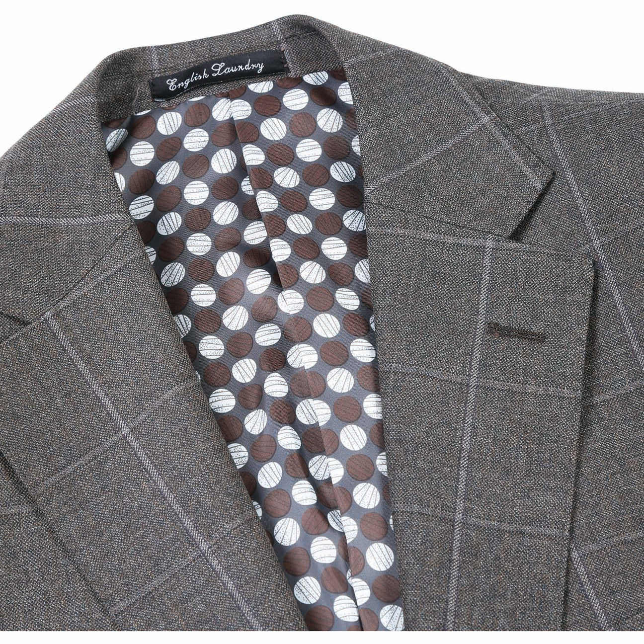 A brown wool suit jacket from English Laundry, featuring notch lapels and a slim fit, is displayed on a mannequin along with a light peach tie and white shirt. This ensemble is crafted from 80% wool.