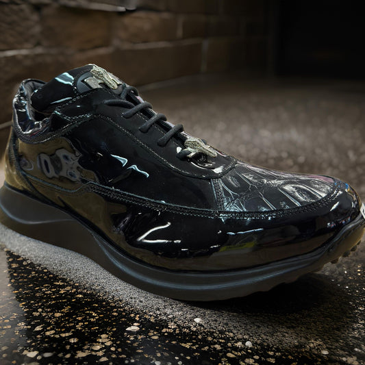 A custom-made Mauri 8900 Black Patent Leather Shoe featuring a baby crocodile texture detail is showcased on a reflective, speckled surface.