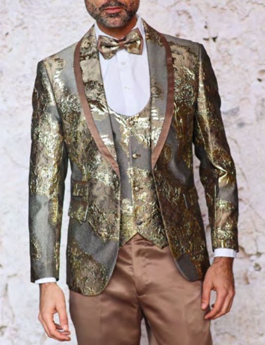 A man wearing the INSOMNIA DELMAS TAUPE Suit by Inserch, featuring a gold and bronze brocade tuxedo with matching vest and bow tie, paired with a white shirt, stands against a textured gray background.