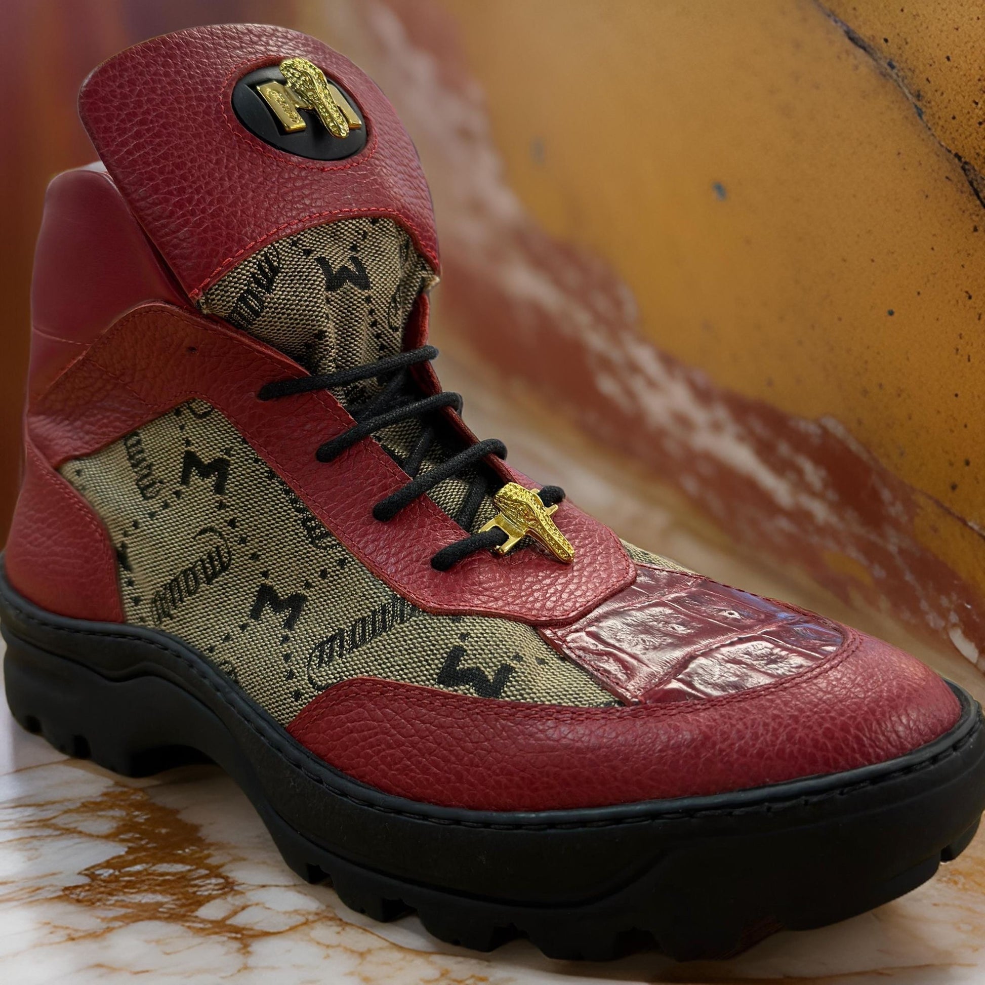 Mauri 3216 Red Boots by Mauri are high-top sneakers with a red and beige design, complete with black laces. They feature a patterned fabric and textured leather upper, similar to custom-made sneakers, and are showcased on a marbled surface.