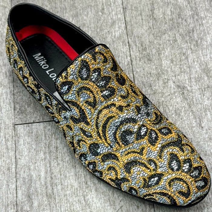 An Exclusive Formal Dress Shoe by UNIQUE DESIGN MENSWEAR, crafted from rich suede leather and adorned with an ornate yellow, black, and silver paisley pattern, rests elegantly on a textured gray floor.