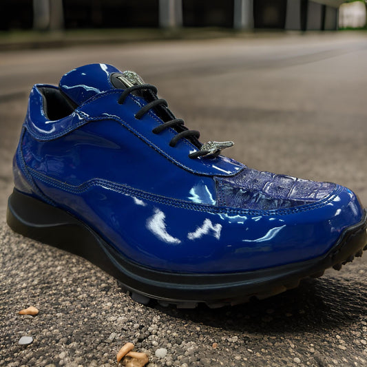 A pair of Mauri 8900 Blue Patent Leather sneakers featuring a glossy, blue textured surface with black laces is placed on a rough, textured ground.