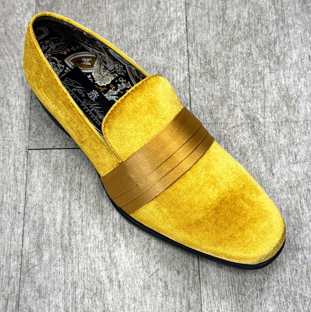 Presenting the Exclusive Formal Dress Shoe Gold 7021 by UNIQUE DESIGN MENSWEAR, a vibrant yellow velvet loafer adorned with a metallic gold band and crafted in Italy. The intricately patterned inner lining enhances its luxurious appeal, all set against an elegant gray wood floor backdrop.