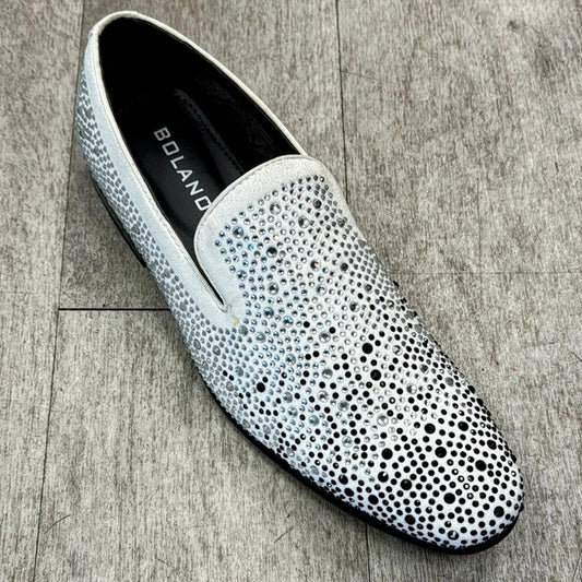 A white slip-on shoe featuring the brand name "UNIQUE DESIGN MENSWEAR" on the insole, adorned with an array of small silver studs, made from genuine leather and displayed on a wooden floor.