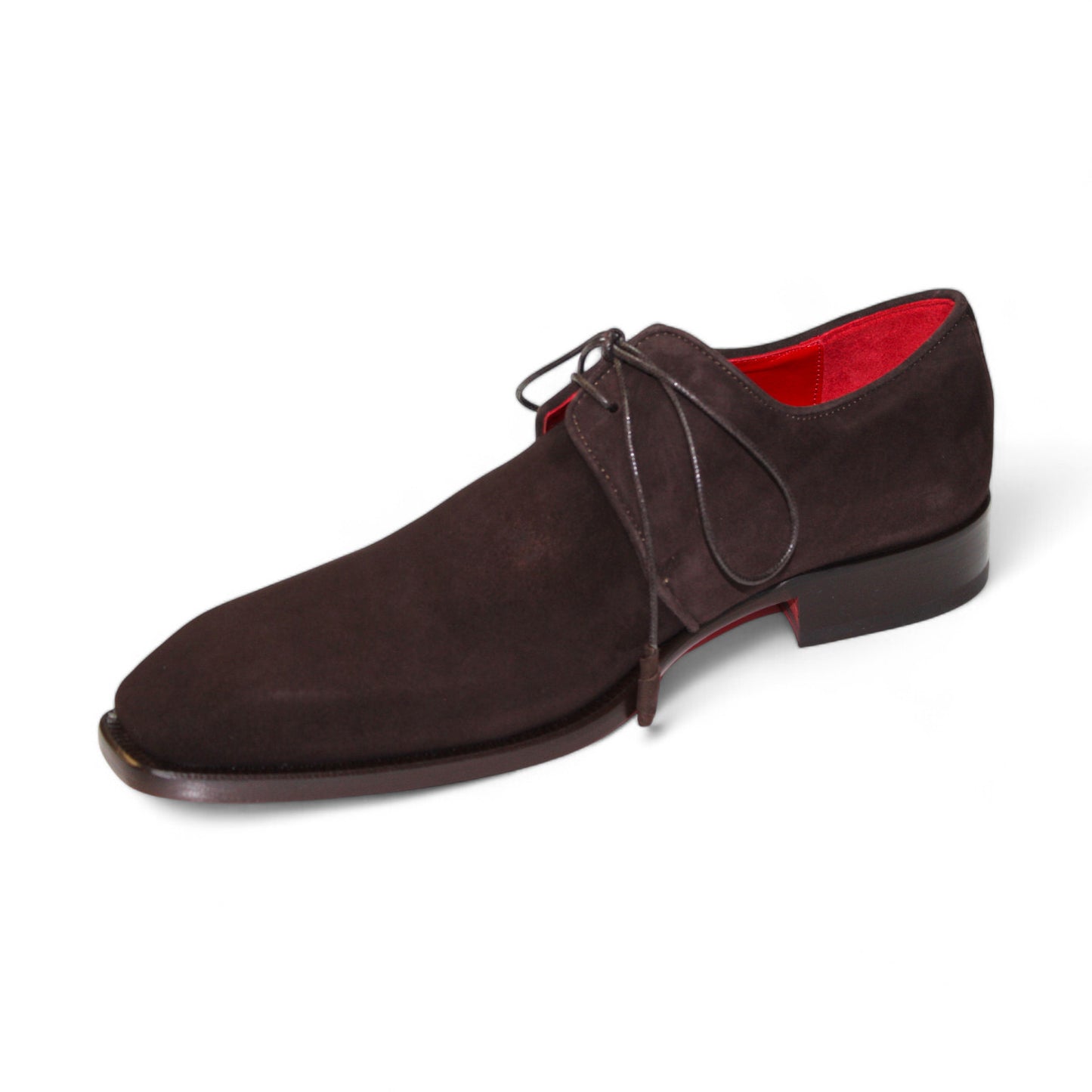 Emilio Franco's "Gabriele" chocolate shoe is a single brown suede dress shoe meticulously crafted in Italy, featuring a striking red interior lining and black laces. The shoe is elegantly showcased from the side and slightly angled for a sophisticated presentation.