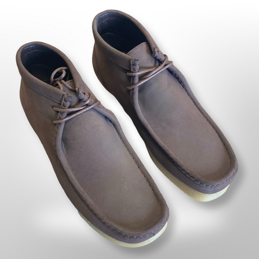 A pair of unique brown leather chukka boots from Unique Design Menswear, known as the Amali Jason Chukka Boots - Brown, featuring a moccasin style with white soles and brown laces, set against a plain background.