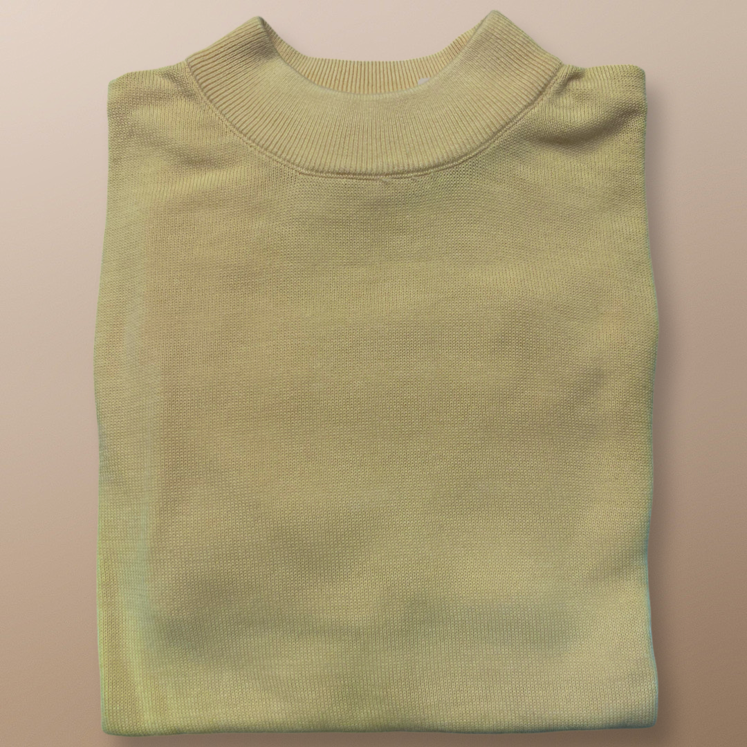 The Inserch Cotton Blend Mock Neck Sweater in Banana Cream 4308-00145 is elegantly folded on a beige surface, highlighting its cozy cotton blend.