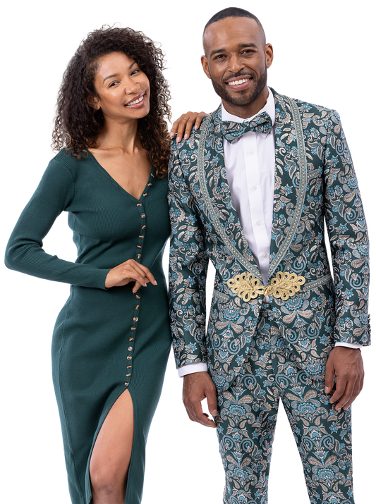 A smiling woman in a dark green dress stands next to a smiling man wearing the EJ Samuel Blue Suit JP124 by EJ SAMUEL, complete with a bow tie.