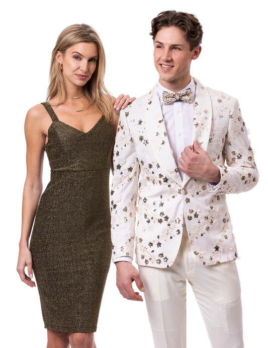 A woman in a sparkly sleeveless dress stands beside a man wearing an EJ SAMUEL floral-patterned blazer, matching pants, and a stylish bow tie from the EJ Samuel Cream Suit JP134 collection.