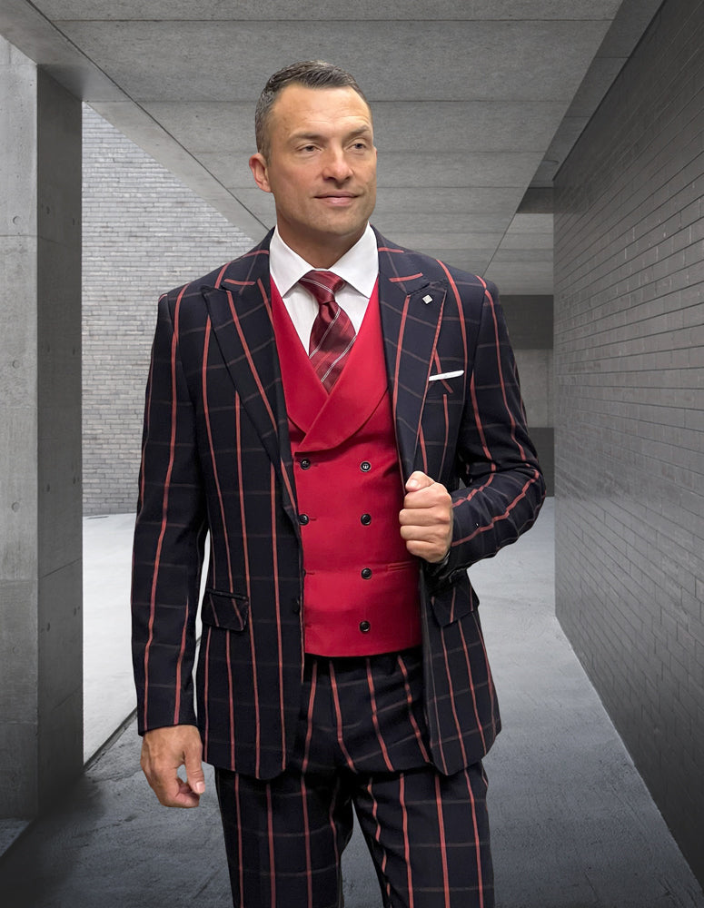 A man dressed in a LUCCI-BLACK-RED suit from Statement Clothing features red and black stripes made from Italian wool. He's standing in a concrete hallway, donning a modern fit red vest and tie.