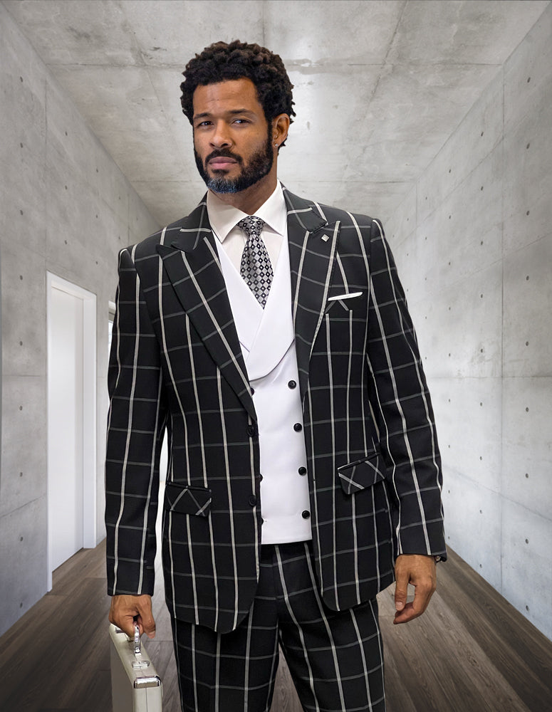 A man with a beard and curly hair is wearing the LUCCI-BLACK-WHITE modern fit suit from Statement Clothing, featuring a black and white checkered design crafted from fine Italian wool, while holding a briefcase in a sleek, concrete hallway.