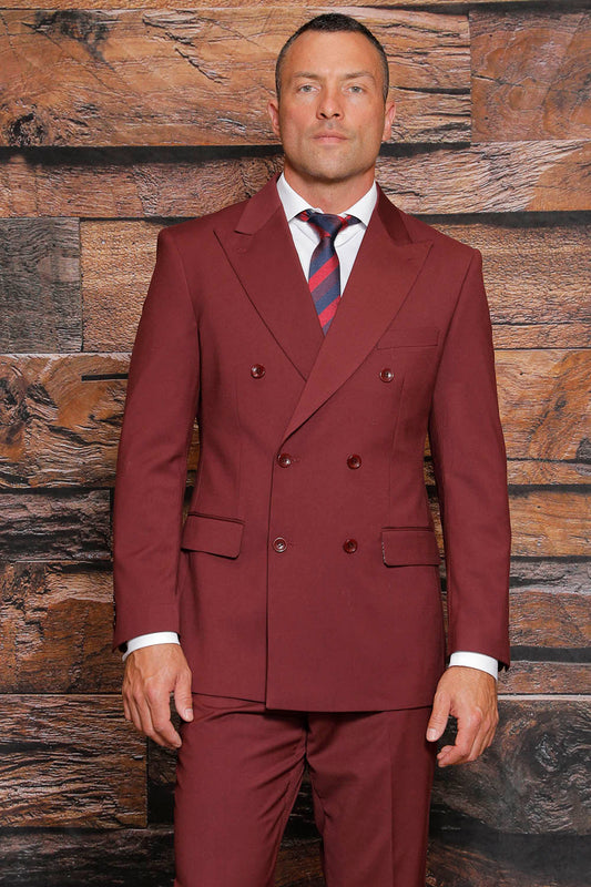 A man in an Insomnia Luna 2PC modern fit burgundy double-breasted suit and striped tie stands stylishly in front of a wooden wall, epitomizing contemporary fashion with his sleek ensemble.