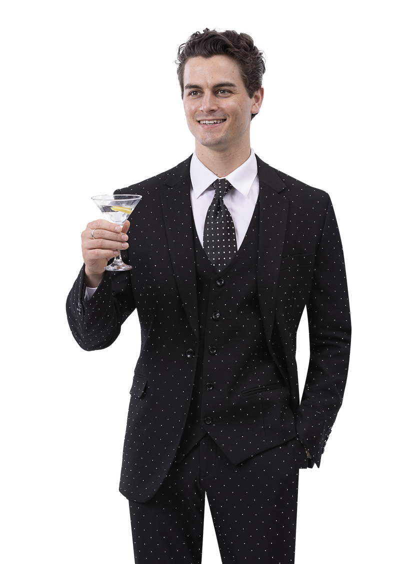 A man in an EJ Samuel Black Suit M2796, known for its modern fit and polka-dot pattern, grins while holding a martini glass, adorned with gleaming diamond studs.