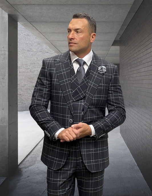 A man wearing the modern fit STATEMENT CLOTHING | MONARI-BLACK Italian wool plaid suit is standing in a concrete hallway, facing slightly to the side.