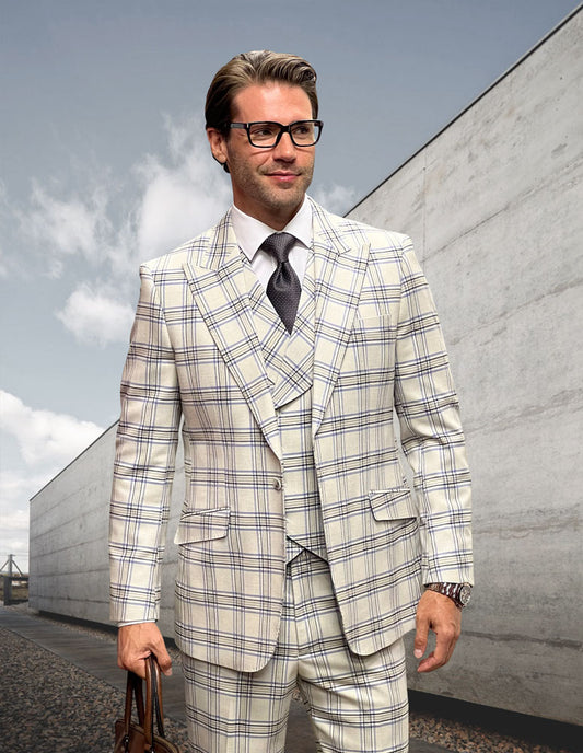 A man in a modern-fit suit from Statement Clothing's MONARI-IVORY collection stands outside, holding a brown bag. His ensemble, featuring an ivory plaid design, is complemented by a white shirt and gray tie, further accentuated by glasses and a watch on his wrist.