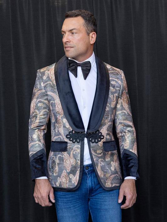 A man wearing the INSOMNIA MZS-566 Tailored Fit Black Fancy Sport Coat by Insomnia is standing against a black background, paired with a matching bow tie, crisp white shirt, and blue jeans.