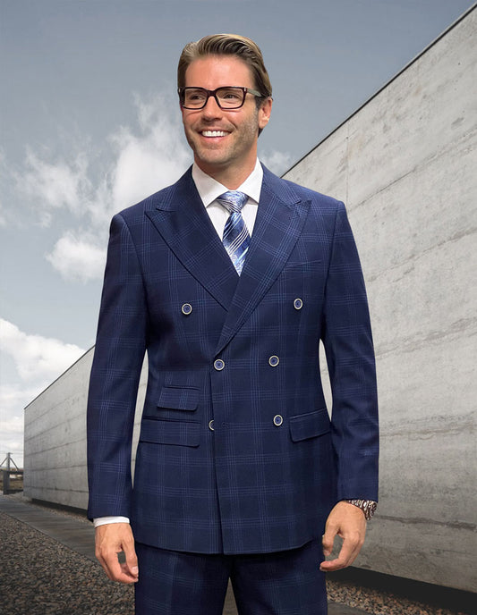 A man stands outdoors wearing the STATEMENT CLOTHING | NAPLES-NAVY, a modern fit plaid double-breasted suit crafted from Italian wool by Statement Clothing, smiling with a gray building and cloudy sky in the background.