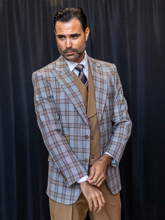 A man in an INSOMNIA PARIS-1 3PC Compose Tailored Fit Copper Suit adjusts his sleeve while standing in front of a black curtain, preparing himself for the spotlight.