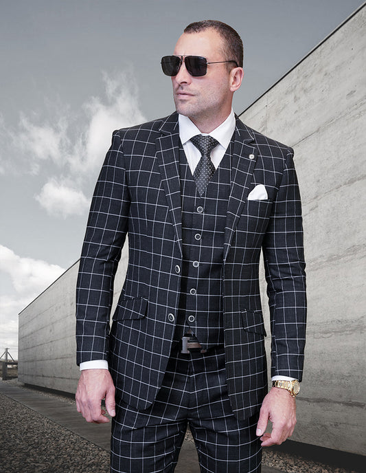 A man dressed in a modern fit suit from Statement Clothing's Pomelo-Black collection and wearing sunglasses stands confidently outdoors against a sleek concrete building backdrop.