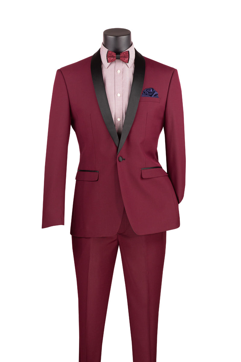 Displayed on a mannequin is the Vinci Slim Fit 2 Piece 1 Button Shawl Collar Tuxedo in Burgundy from Vinci Suits, featuring a black lapel. It comes with a matching bow tie and blue pocket square, offering wrinkle-resistant fabric for pristine elegance.