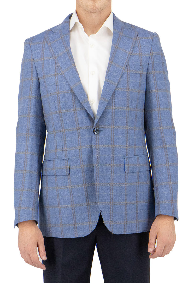 A person stylishly clad in a Tiglio Luxe Dolcetto modern fit jacket, featuring a sky blue base with gold and brown windowpane pattern, crafted from pure wool, complemented by a pristine white shirt, shown from the neck down.