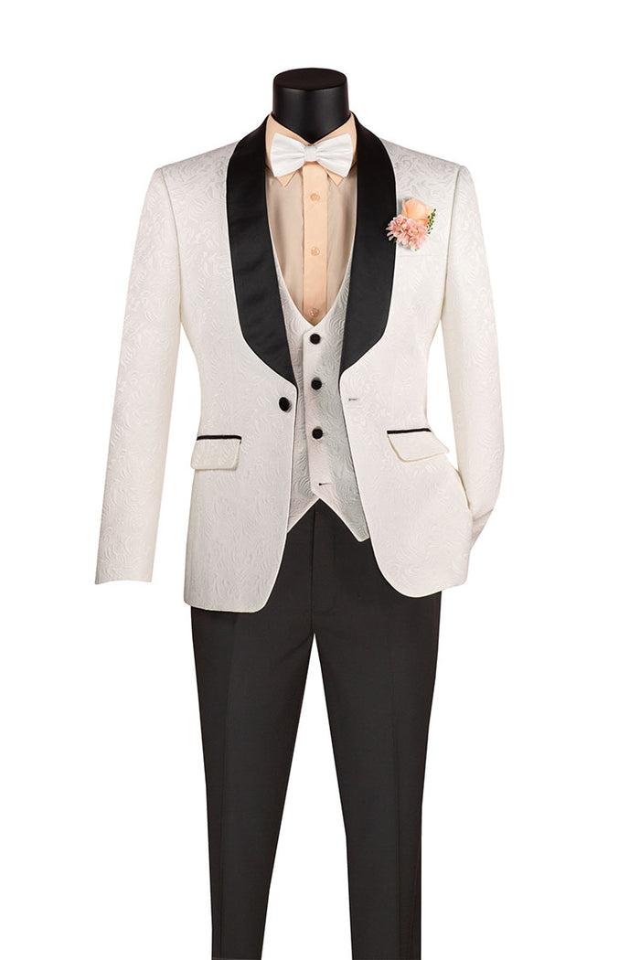 A mannequin displays the Vinci Suits' Vinci Slim Fit 3 Piece Single Button Jacquard Fabric Tuxedo in White (TVSJ-1), featuring a white jacquard pattern jacket with black lapels. The ensemble is complete with a peach shirt, beige vest, and wrinkle-resistant black pants, while a decorative flower adorns the left lapel for an elegant touch.