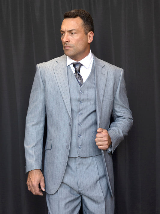 Dressed in the INSOMNIA VENETIAN 3PC Regular Fit Grey Suit by Insomnia, a man stands against a dark curtain, looking to the side, with sharp pleat pants and tie completing his ensemble.