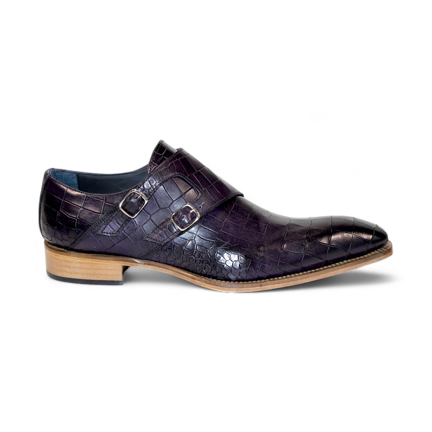 The Duca Di Matiste Vergato in purple is a single dark embossed leather monk strap shoe featuring double buckles and a light wooden sole, elegantly displayed on a white background. Made in Italy by Duca Di Matiste, this exquisite footwear exemplifies impeccable craftsmanship and material quality.