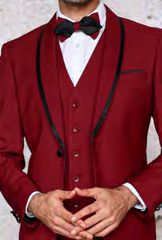 A man in the Insomnia SUNSET 3PC Slim Fit Burgundy Black Tuxedo Suit with a sleek, black bow tie is wearing a reversible vest, hands clasped in front.