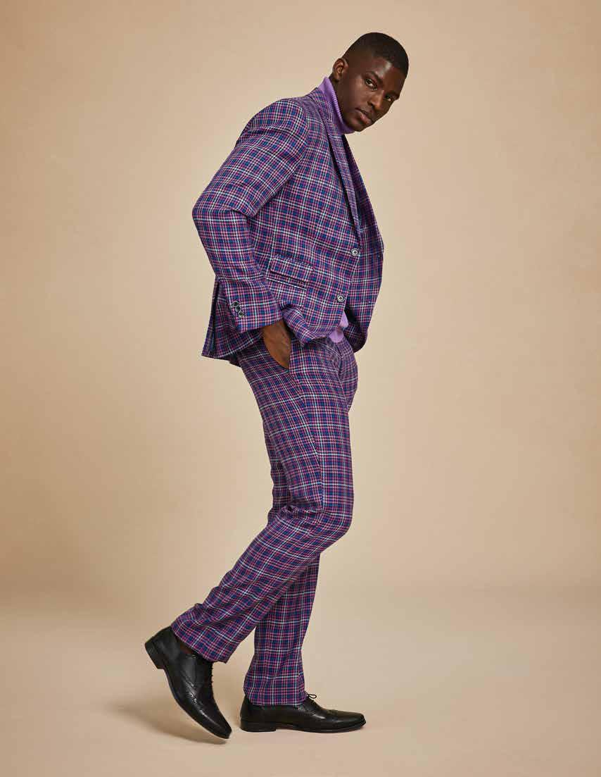 A person wearing the Inserch Micro Houndstooth Check Peak Lapel Suit in purple, featuring a subtle printed lining, paired with a purple turtleneck stands against a plain background.