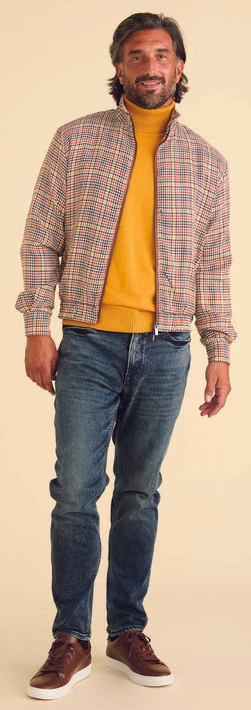 A man wearing the Inserch Micro Check Full Zip Jacket JS265-64 Mocha, featuring a unique print lining, pairs it with a yellow turtleneck, blue jeans, and brown sneakers as he stands against a beige background.