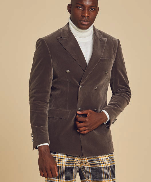 A person wearing the Inserch DB Velvet Blazer BL502-33 in grey, paired with a white turtleneck and plaid pants, stands against a beige background.