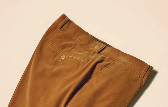 A pair of neatly folded Inserch Velvet Pants P502-184 in Brown Sugar, featuring a modern fit and a buttoned back pocket, lying on a light surface.