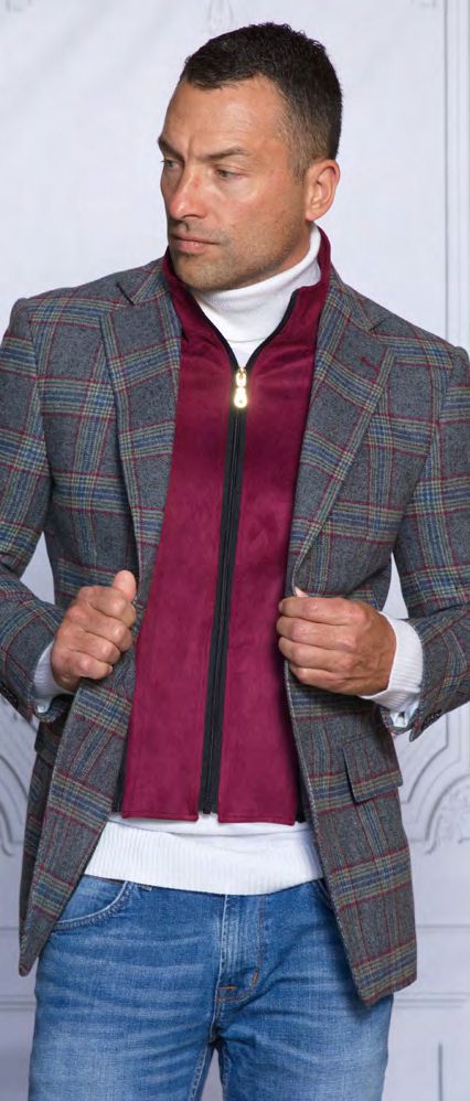 A man wearing the Insomnia INSOMNIA MZW-535 Tailored Fit Charcoal Wool Blend Blazer over a red zip-up and white turtleneck looks to the side. He is also wearing blue jeans.