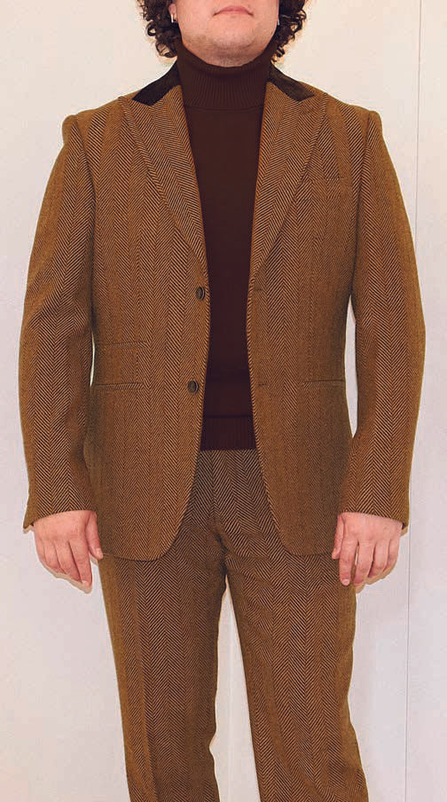 The person is elegantly dressed in a chocolate Inserch BL273-24 Herringbone Blazer with peak lapels, complemented by a dark brown turtleneck.