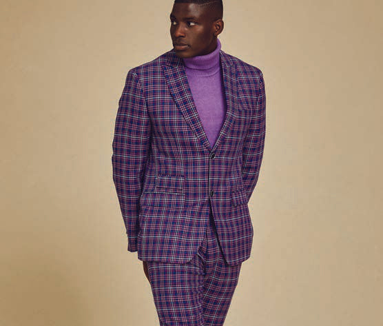 A person wearing the Inserch Micro Houndstooth Check Peak Lapel Suit in purple, featuring a subtle printed lining, paired with a purple turtleneck stands against a plain background.