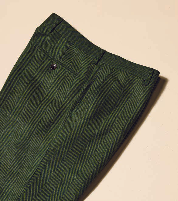 A person is wearing Inserch's Herringbone Pants P263-19 Olive paired with white sneakers against a beige background.