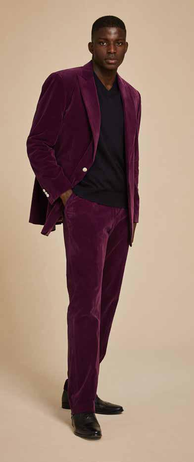 A person wearing the Inserch Single Breasted Peak Lapel Velvet Suit BL007-166 in deep violet, paired with black shoes, stands against a beige background.