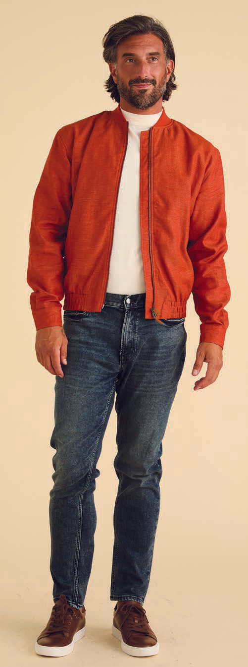 A person wearing the Inserch Linen Bomber Jacket JS660-00109 in Burnt Orange, featuring a ribbed collar and matching pants, stands confidently against a beige background, with the metal zipper adding a touch of edgy style.