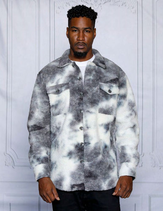 A man stands against a neutral background, wearing the Insomnia ICELAND grey button sweater shirt, made from a poly fleece blend in a black and white tie-dye pattern. His expression is serious.