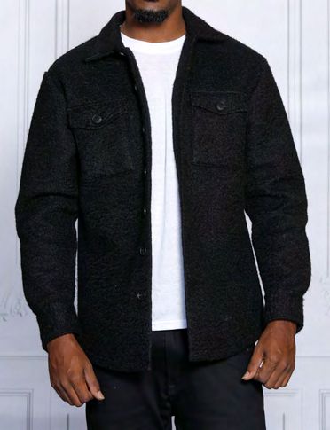 A person is wearing an Insomnia Iceland Black Poly Fleece Blend Button Sweater Shirt over a crisp white shirt, with a neutral, light-colored wall in the background.