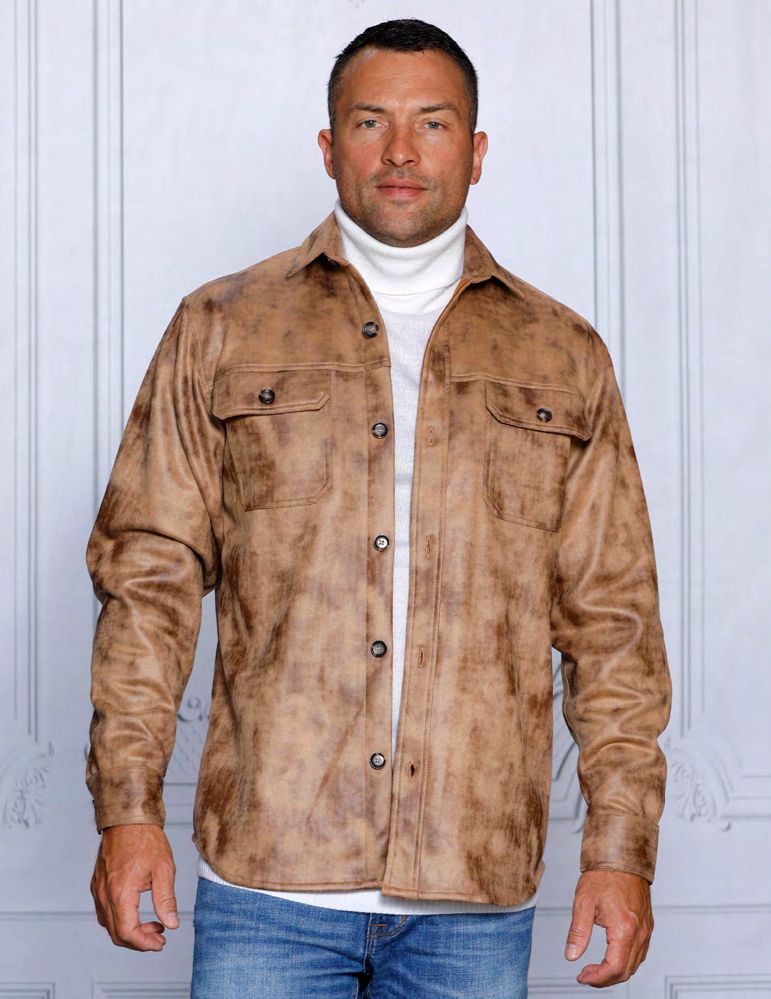 A man wearing a stylish Insomnia camel vegan suede spandex sweater shirt over a white turtleneck and blue jeans stands against a light gray paneled background.