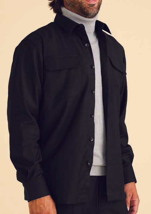 A person wearing the Inserch Two-Pocket Shirt SE004-01 in black over a gray turtleneck sweater stands against a beige background.