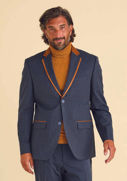 A man dressed in the Inserch Denim Blazer BL274-10 in denim blue, complemented by brown accents and a brown turtleneck, stands against a neutral backdrop, exuding both elegance and style.